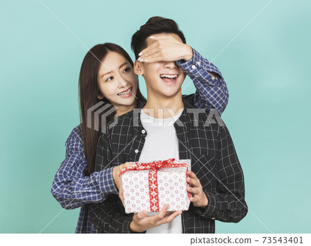 young woman giving present to boyfriend young woman giving present to boyfriend 73543401