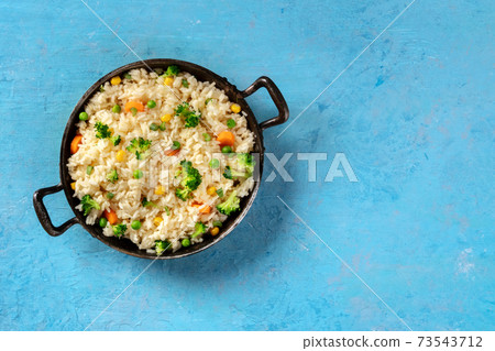 Vegetable rice in a skillet, overhead shot on a blue background 73543712