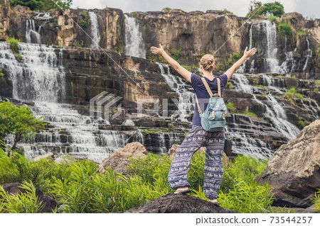 Young woman hiker, tourist on the background of Amazing Pongour Waterfall is famous and most beautiful of fall in Vietnam. Not far from Dalat city estimate 45 Km. Dalat, Vietnam 73544257