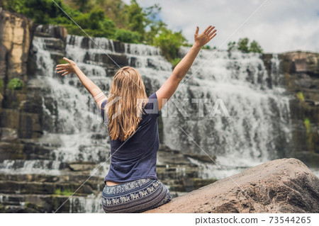 Young woman hiker, tourist on the background of Amazing Pongour Waterfall is famous and most beautiful of fall in Vietnam. Not far from Dalat city estimate 45 Km. Dalat, Vietnam 73544265
