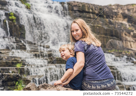 Mother and son hikers, tourists on the background of Amazing Pongour Waterfall is famous and most beautiful of fall in Vietnam. Not far from Dalat city estimate 45 Km. Dalat, Vietnam 73544272