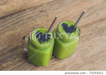 Fresh green smoothie with banana and spinach with heart of sesame seeds. Love for a healthy raw food concept Fresh green smoothie with banana and spinach with heart of sesame seeds. Love for a healthy raw food concept 73544811