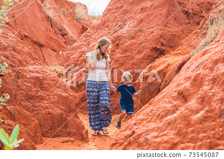 Mother and son travelers in red canyon near Mui Ne, southern Vietnam. Traveling with children concept Mother and son travelers in red canyon near Mui Ne, southern Vietnam. Traveling with children concept 73545087