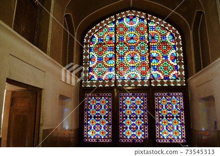 Yazd, Iran. The beautiful symmetrical colorful stained glass windows of the Pavilion under the wind catcher at Dolat Abad Garden. UNESCO World Heritage Site. Yazd, Iran. The beautiful symmetrical colorful stained glass windows of the Pavilion under the wind catcher at Dolat Abad Garden. UNESCO World Heritage Site. 73545313