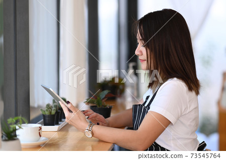 Female entrepreneur in an apron using a digital... - Stock Photo ...