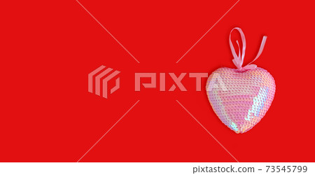 Pink wicker heart symbol made of sequins lies on the red background to Valentine's Day. Top view. Flat lay. Greeting card, concept of the holiday of lovers. 73545799
