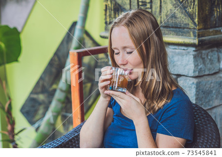 Pretty young woman holding a cup of hot citrus tea or hot lemonade 73545841