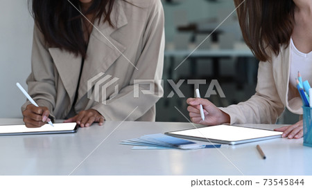 Cropped shot of two young creative start up woman using digital tablet and discussing ideas in board room. 73545844