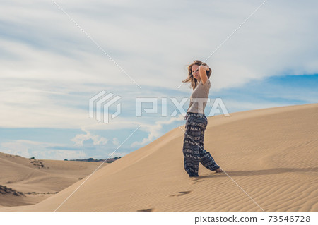 young woman in sandy desert walk alone against sunset cloudy sky. Texture of sand 73546728