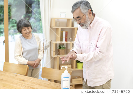 Senior man doing alcohol disinfection Senior man doing alcohol disinfection 73546760