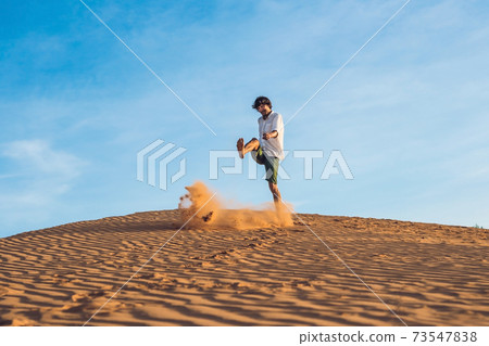 A man is kicking sand in a red desert. Splash of anger concept 73547838