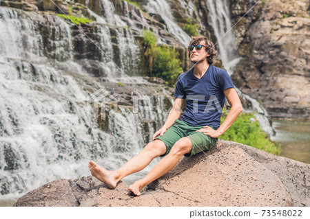 Man hiker, tourist on the background of Amazing Pongour Waterfall is famous and most beautiful of fall in Vietnam. Not far from Dalat city estimate 45 Km. Dalat, Vietnam 73548022