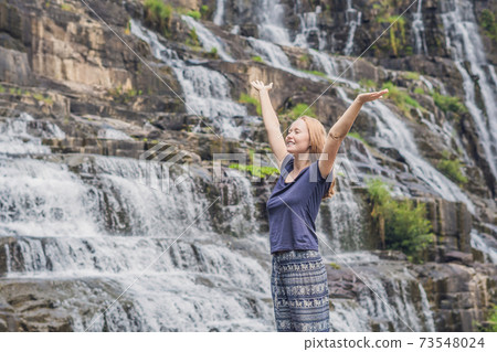 Young woman hiker, tourist on the background of Amazing Pongour Waterfall is famous and most beautiful of fall in Vietnam. Not far from Dalat city estimate 45 Km. Dalat, Vietnam 73548024
