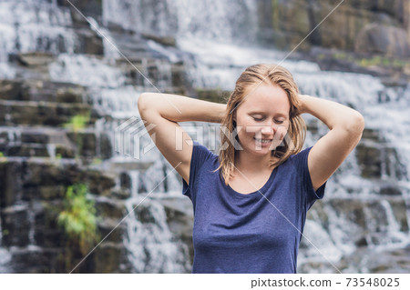 Young woman hiker, tourist on the background of Amazing Pongour Waterfall is famous and most beautiful of fall in Vietnam. Not far from Dalat city estimate 45 Km. Dalat, Vietnam 73548025