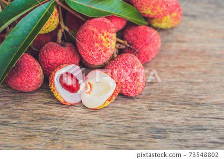 Fresh litchi fruit on an old wooden background Fresh litchi fruit on an old wooden background 73548802