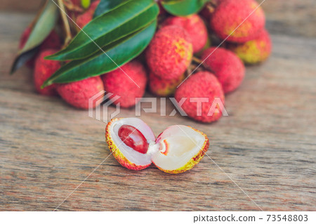 Fresh litchi fruit on an old wooden background Fresh litchi fruit on an old wooden background 73548803