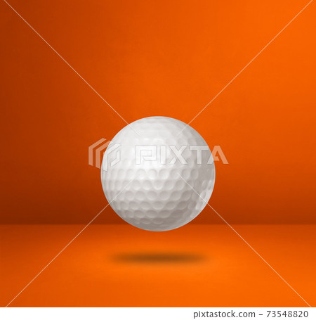 White golf ball on a orange studio background 73548820