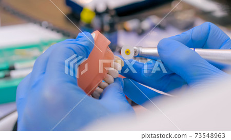 Dental technician working with dental prosthetics - close up view Dental technician working with dental prosthetics - close up view 73548963