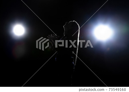 Silhouette of woman praying isolated on dark background in lanterns light Silhouette of woman praying isolated on dark background in lanterns light 73549168