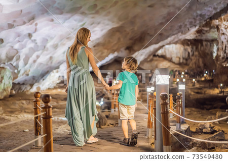 Mom and son tourists in Hang Sung Sot Grotto Cave of Surprises, Halong Bay, Vietnam. Traveling with children concept. Tourism after coronavirus Mom and son tourists in Hang Sung Sot Grotto Cave of Surprises, Halong Bay, Vietnam. Traveling with children concept. Tourism after coronavirus 73549480