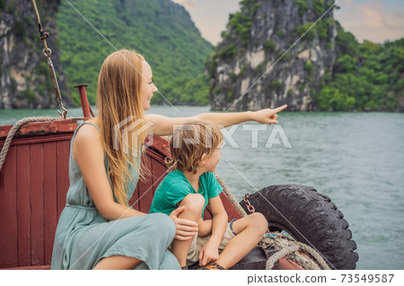 Mom and son travelers is traveling by boat in Halong Bay. Vietnam. Travel to Asia, happiness emotion, summer holiday concept. Traveling with children concept. After COVID 19. Picturesque sea landscape 73549587