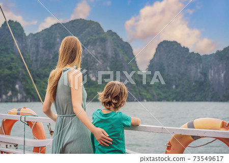 Mom and son travelers is traveling by boat in Halong Bay. Vietnam. Travel to Asia, happiness emotion, summer holiday concept. Traveling with children concept. After COVID 19. Picturesque sea landscape Mom and son travelers is traveling by boat in Halong Bay. Vietnam. Travel to Asia, happiness emotion, summer holiday concept. Traveling with children concept. After COVID 19. Picturesque sea landscape 73549617