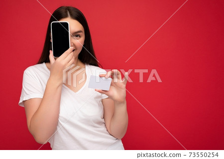 Photo of attractive happy young brunette lady wearing casual white t-shirt isolated over red Photo of attractive happy young brunette lady wearing casual white t-shirt isolated over red 73550254