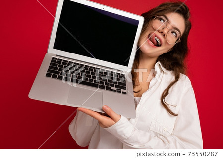 Crazy mad beautiful brunette curly young woman holding computer laptop wearing glasses white shirt 73550287