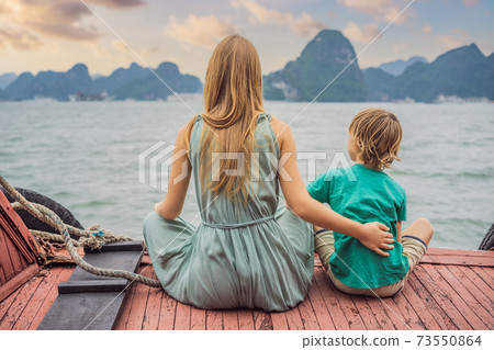 Mom and son travelers is traveling by boat in Halong Bay. Vietnam. Travel to Asia, happiness emotion, summer holiday concept. Traveling with children concept. After COVID 19. Picturesque sea landscape Mom and son travelers is traveling by boat in Halong Bay. Vietnam. Travel to Asia, happiness emotion, summer holiday concept. Traveling with children concept. After COVID 19. Picturesque sea landscape 73550864