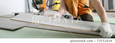 Specialist hold laminate in his handand put it on floor. 73552034