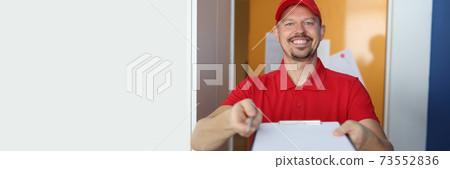 Smiling male courier holds out clipboard and pen. Smiling male courier holds out clipboard and pen. 73552836