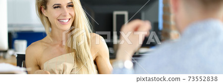 Smiling businesswoman sits at table holding a pen and communicates with colleague. Smiling businesswoman sits at table holding a pen and communicates with colleague. 73552838