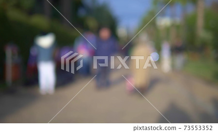blurred background. people walking in the park along the alley on a sunny day blurred background. people walking in the park along the alley on a sunny day 73553352