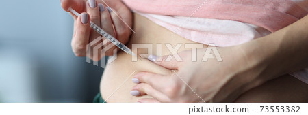 Woman gives an injection in the stomach. 73553382