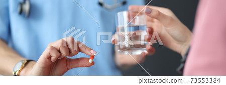 Doctor hands the patient pill and glass of water. 73553384