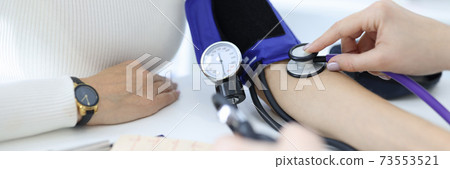 Doctor measuring blood pressure on patients arm in clinic closeup 73553521