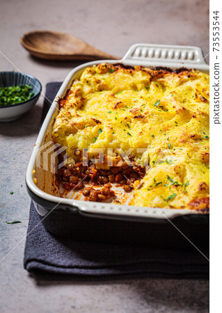 Vegan shepherd's pie with lentils and mashed potatoes in black backing dish. Vegan healthy food concept. Vegan shepherd's pie with lentils and mashed potatoes in black backing dish. Vegan healthy food concept. 73553544