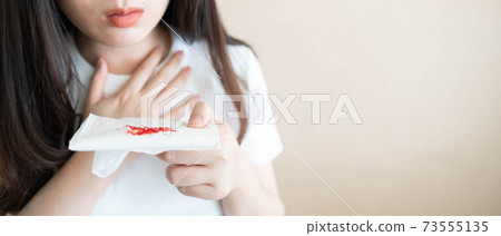 Woman have a coughing up blood and chest pain. Close up of hands holding tissue paper with bloody sputum. Cause of hemoptysis include TB, lung cancer, bronchitis, pneumonia or pulmonary embolism. 73555135