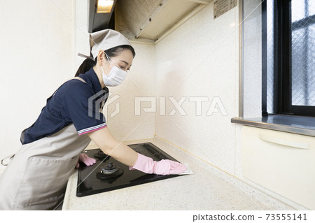 Female house cleaning worker cleaning a gas stove 73555141
