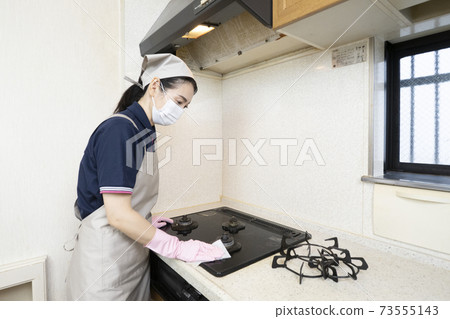 Female house cleaning worker cleaning a gas stove 73555143