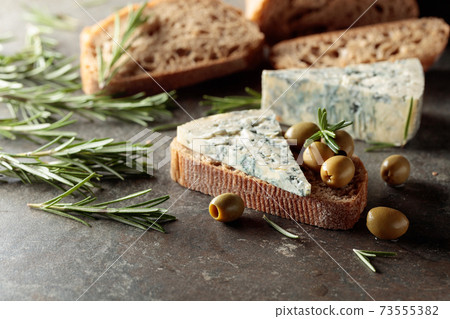 Blue cheese with green olives, rosemary, and bread. Blue cheese with green olives, rosemary, and bread. 73555382