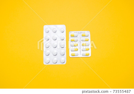 Medical capsules, pills on a yellow background. 73555487