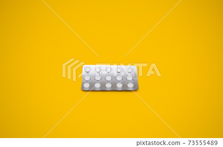 Medical capsules, pills on a yellow background. 73555489
