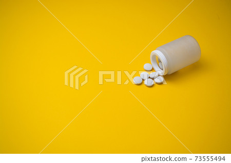 Scattered medicine from jars on a yellow background Scattered medicine from jars on a yellow background 73555494