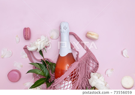 Spring composition with rose sparkling wine, white peonies and macarons 73556059