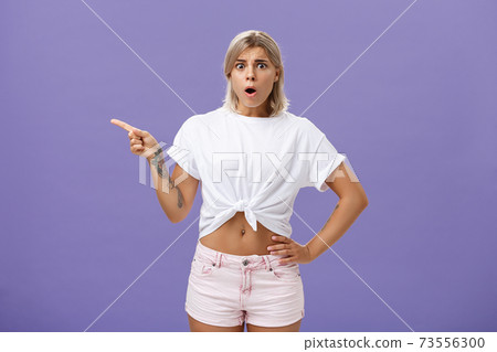 Girl being unhappy with unfair thing happened. Shocked displeased complaining, confused woman with tanned skin blond hair and tattoos opening mouth and frowning from jealousy or regret pointing left Girl being unhappy with unfair thing happened. Shocked displeased complaining, confused woman with tanned skin blond hair and tattoos opening mouth and frowning from jealousy or regret pointing left 73556300