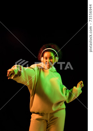 African-american woman's portrait isolated on dark studio background in orange-green neon light African-american woman's portrait isolated on dark studio background in orange-green neon light 73556944