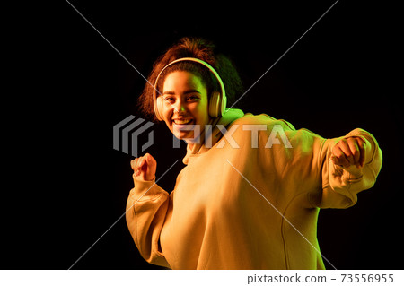 African-american woman's portrait isolated on dark studio background in orange-green neon light 73556955