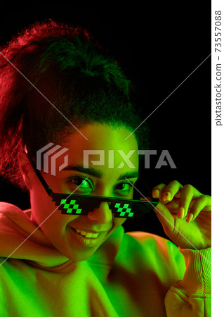 African-american woman's portrait isolated on dark studio background in multicolored neon light 73557088