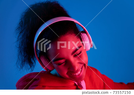 African-american woman's portrait isolated on blue studio background in multicolored neon light 73557150